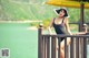 A woman in a black bathing suit and hat posing on a balcony.