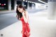 A woman in a red dress is walking down the street.