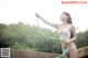 A woman in a bikini holding a hose.