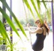 A woman in a black bathing suit swinging on a swing.