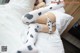 A woman laying on top of a bed in a white and black outfit.