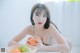 A woman sitting at a table with a bowl of fruit.