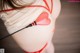 A woman in a red and white lingerie with a red heart on her butt.