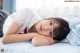 A young girl laying on a bed with her head on the pillow.