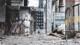 A woman in a white suit standing in an abandoned building.