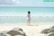 A girl standing on a beach next to the ocean.