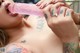 A woman with tattoos is sucking a pink dildo.