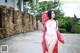 A woman in a white dress and a red kimono posing for a picture.